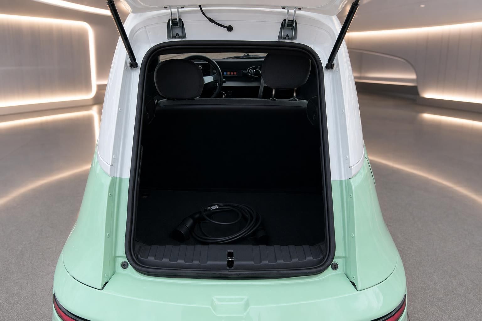 Geöffneter Kofferraum eines mintgrünen Elektroautos mit Ladekabel im Innenraum