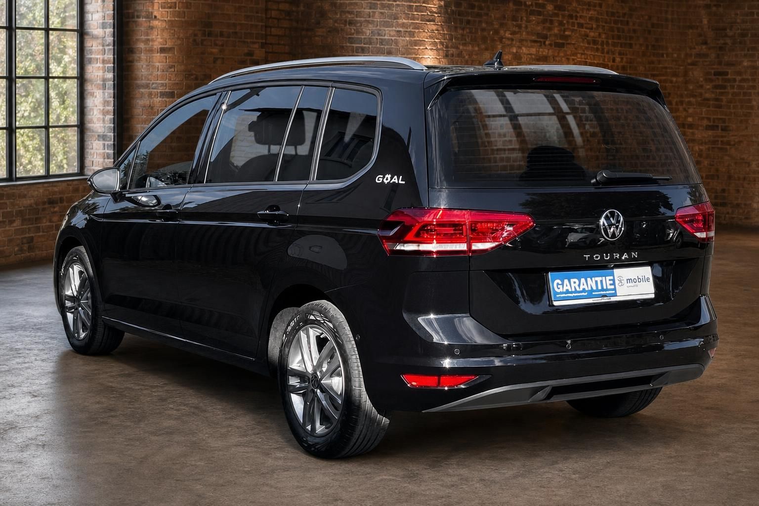 VW Touran schwarz Heckansicht schraeg in Lagerhalle