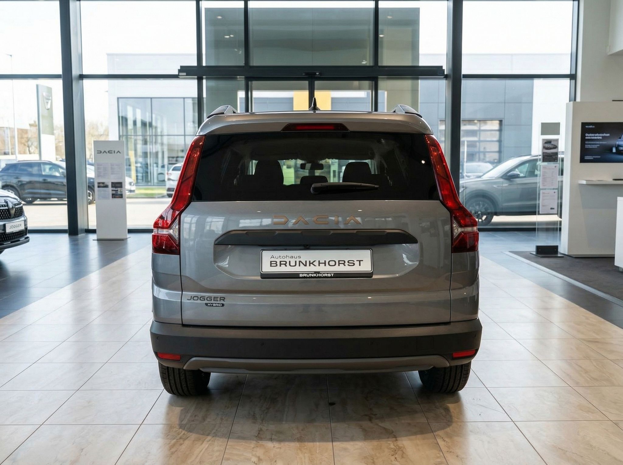 Dacia Jogger Heckansicht grau metallic mit Hybrid-Badge im Autohaus-Showroom