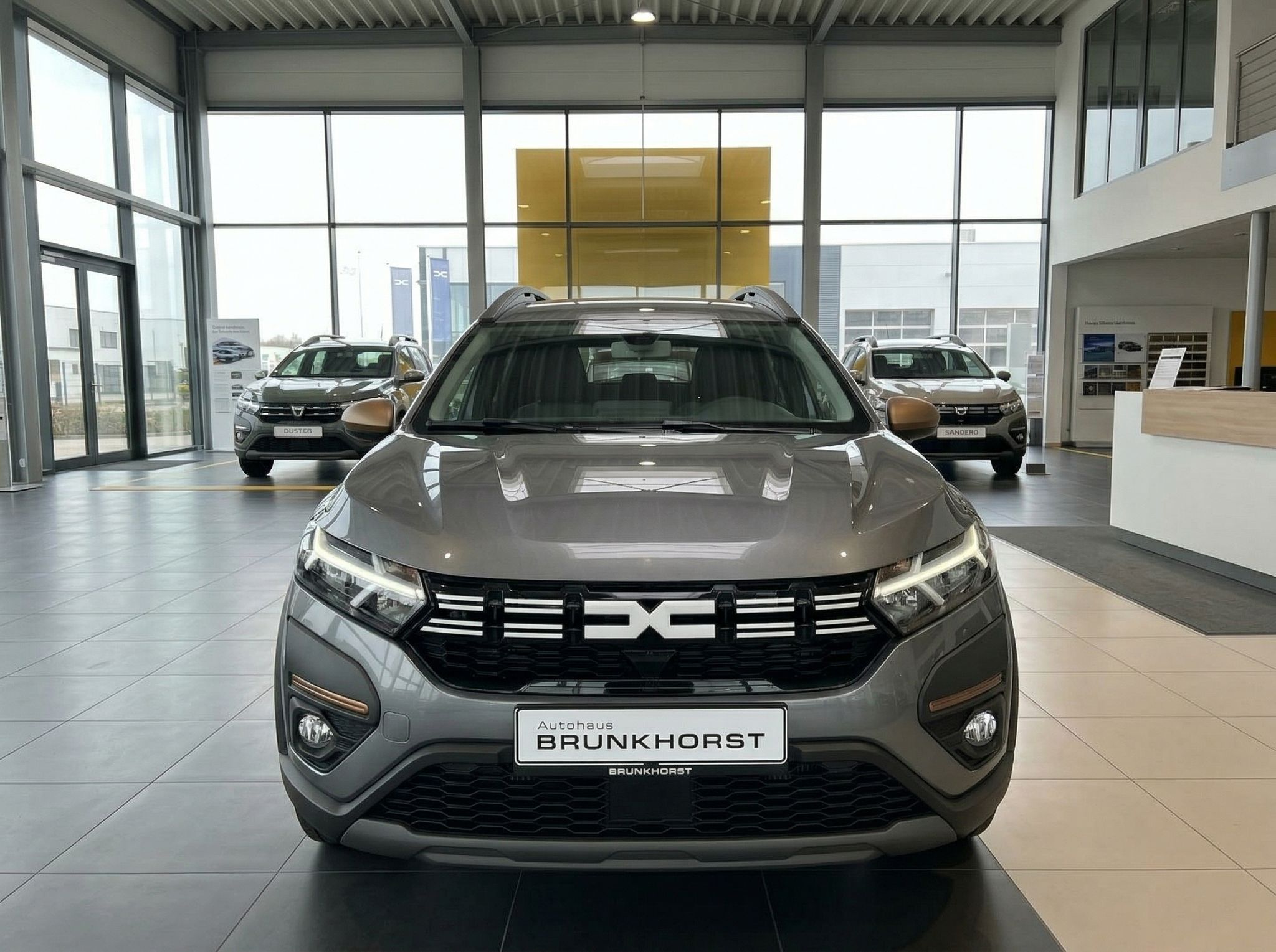 Dacia Jogger Frontansicht grau metallic mit schwarzem Kühlergrill im Autohaus-Showroom