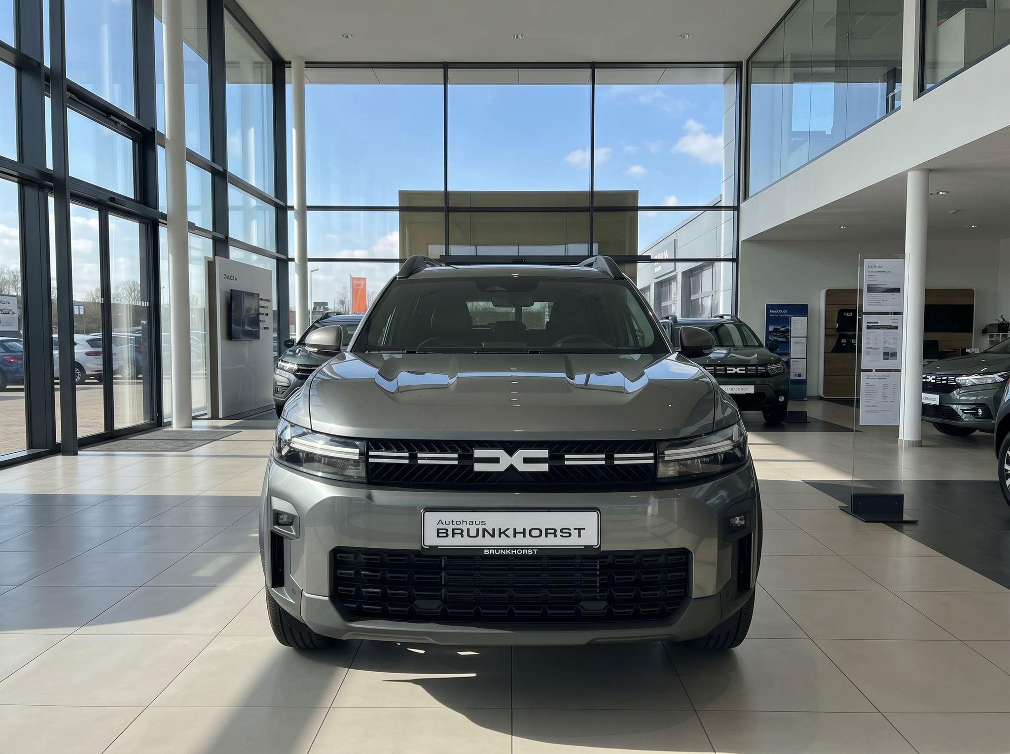 Dacia SUV Frontansicht in silbergrau mit LED-Scheinwerfern im modernen Autohaus-Showroom