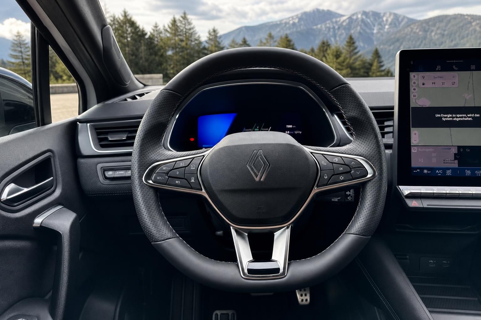 Renault Innenraum mit Lenkrad und digitalem Cockpit vor Bergkulisse