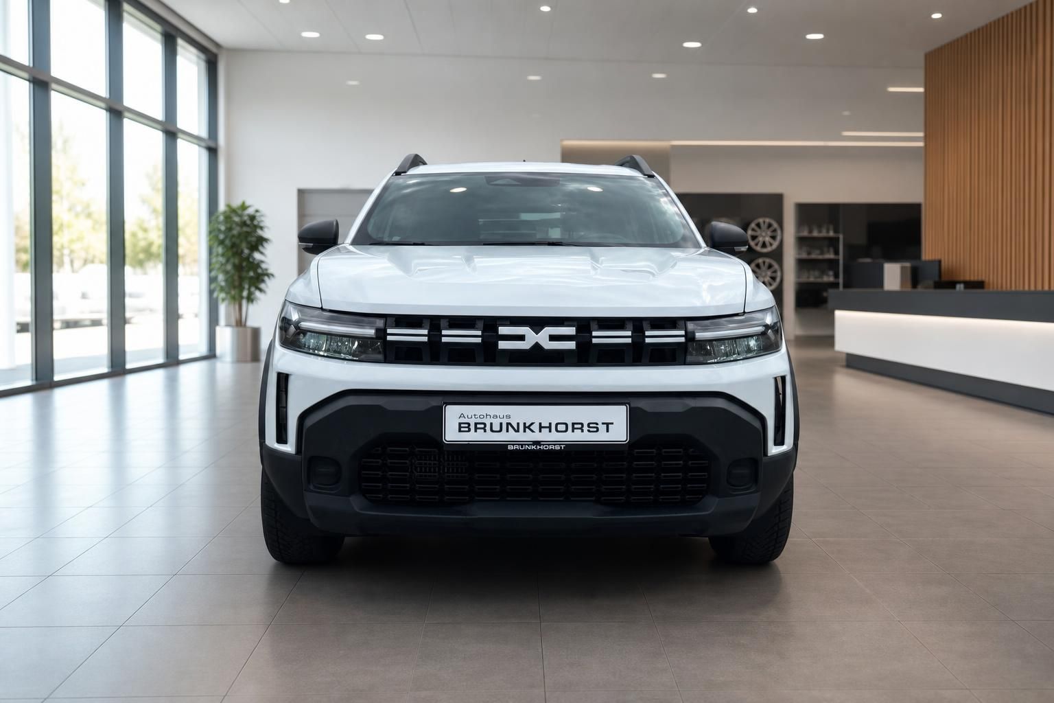 Frontansicht weißer Dacia SUV mit markanter Kühlergrillle im Autohaus