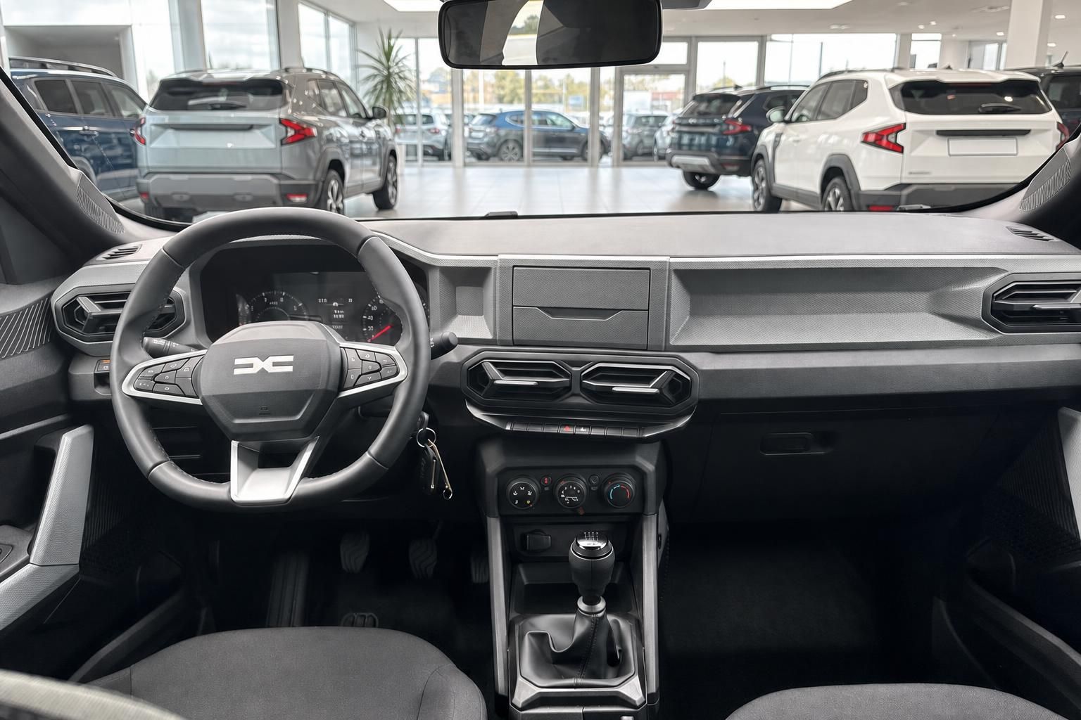 Cockpit-Ansicht Dacia mit Armaturenbrett und Blick in Autohaus-Ausstellung