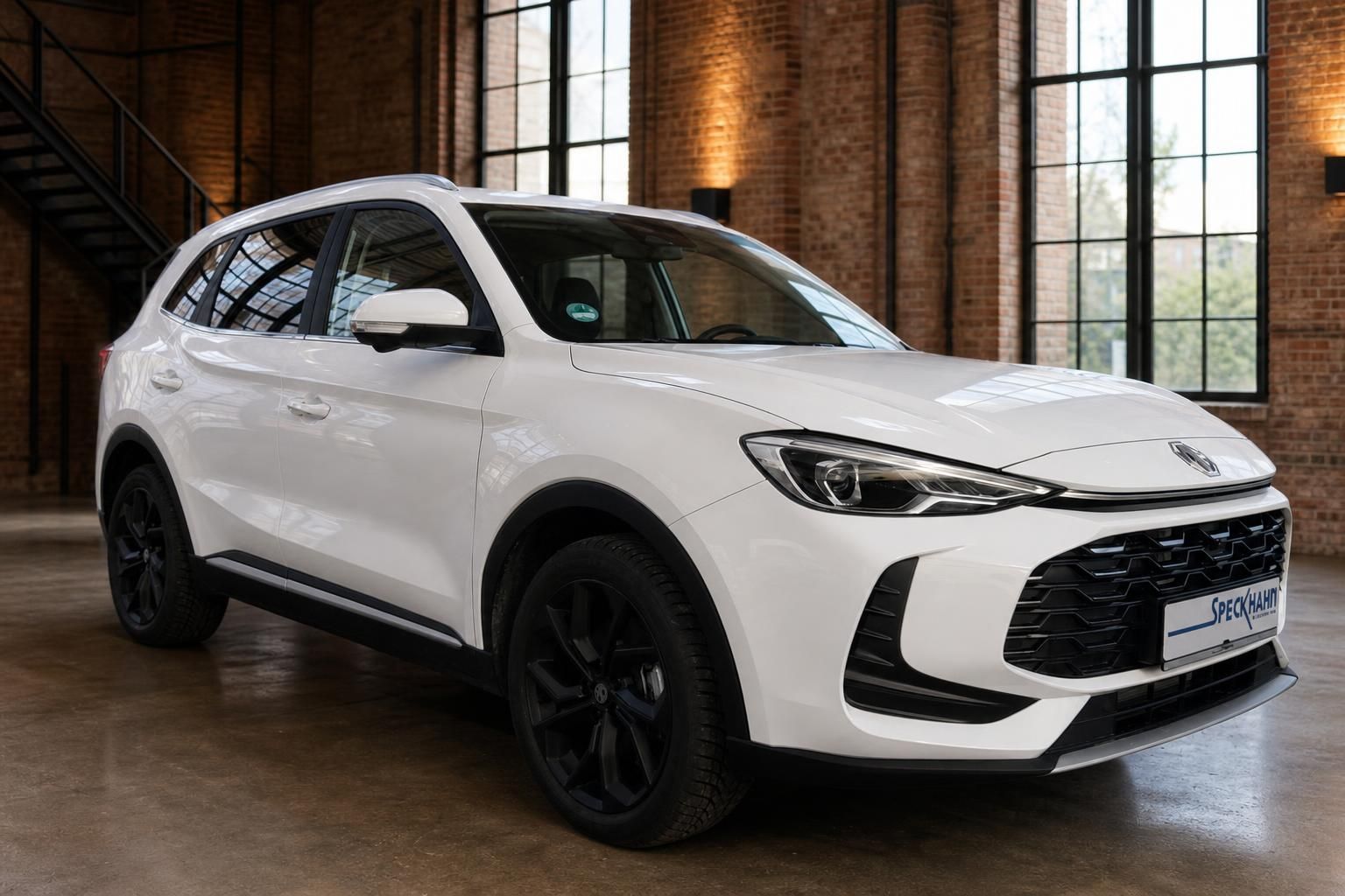 MG ZS Hybrid+ weiß, seitliche Frontansicht im Industrie-Ambiente