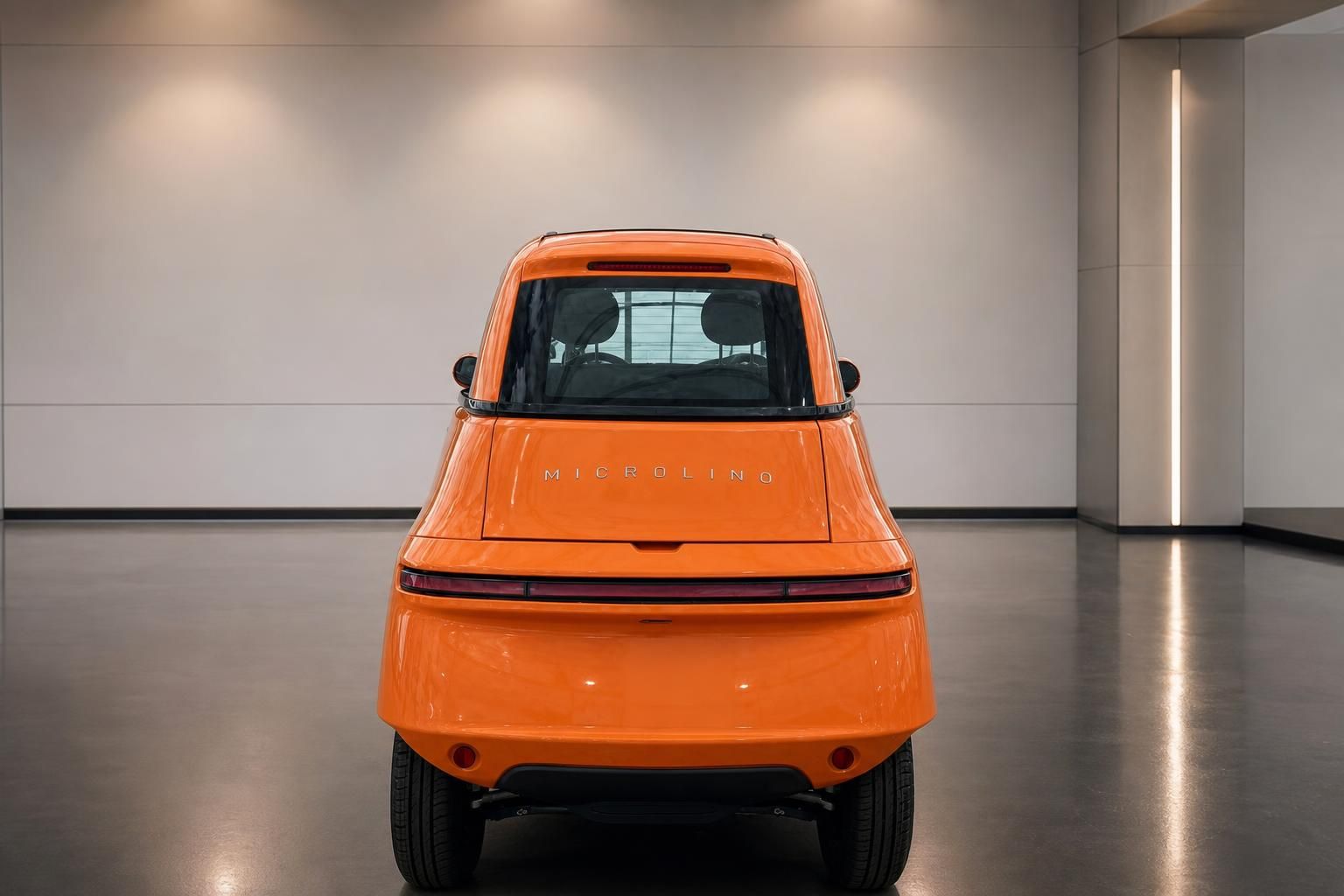 Orange Microlino Elektroauto Heckansicht mit MICROLINO Schriftzug, LED-Rückleuchten in Showroom