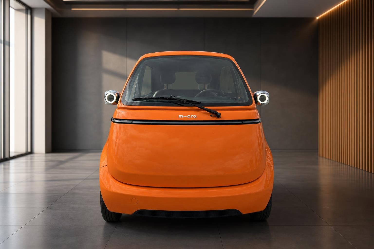 Orange Microlino Elektrofahrzeug Frontansicht mit charakteristischen runden Scheinwerfern
