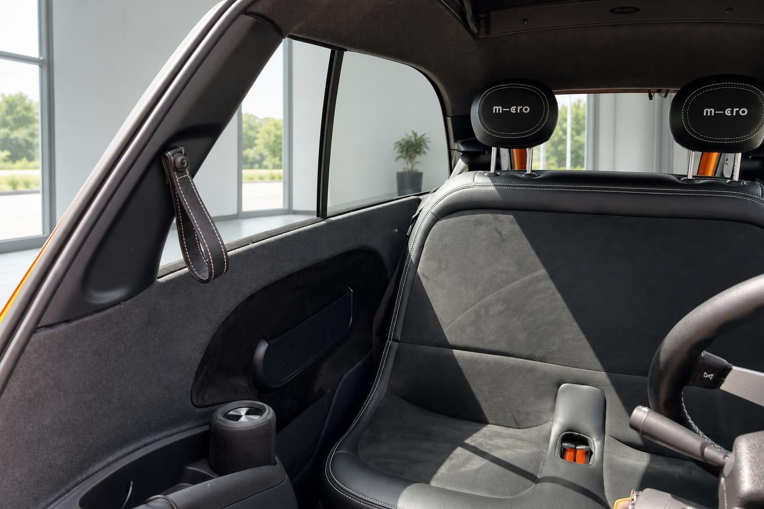 Microlino Elektroauto Innenraum mit grauen Sitzen, Kopfstützen mit m-ero Logo und Türgriff