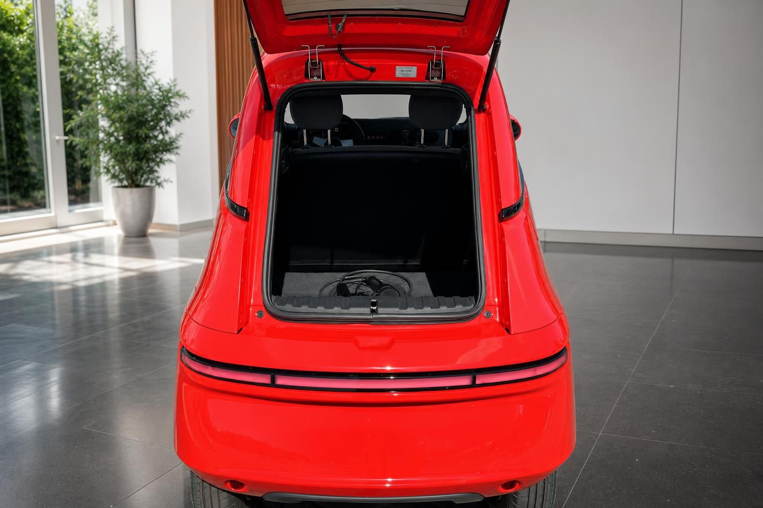 Roter Sportwagen mit geöffnetem Kofferraum und Heckansicht im Showroom
