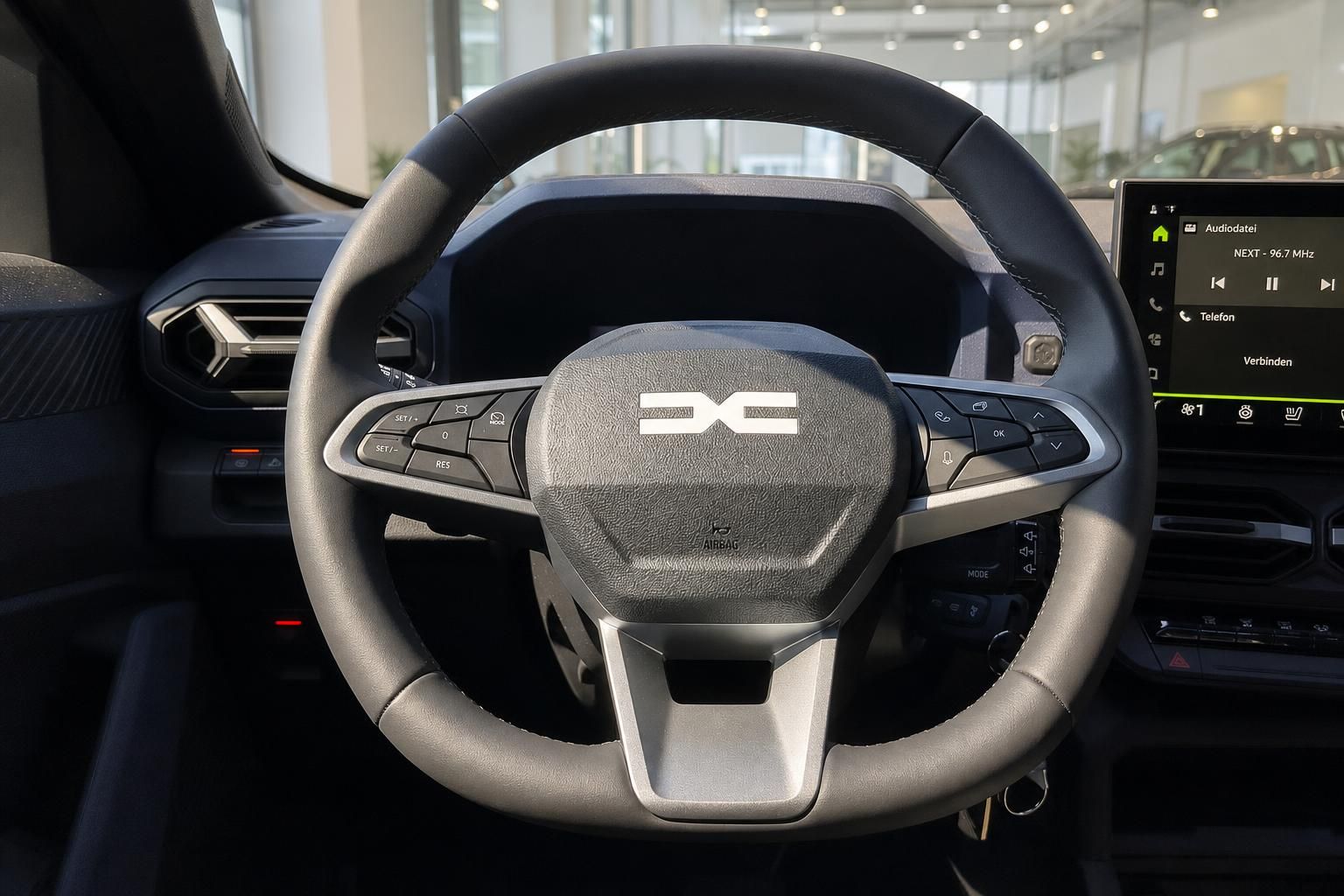 Lenkrad mit Multifunktionstasten und Infotainment-Display im Fahrzeuginnenraum