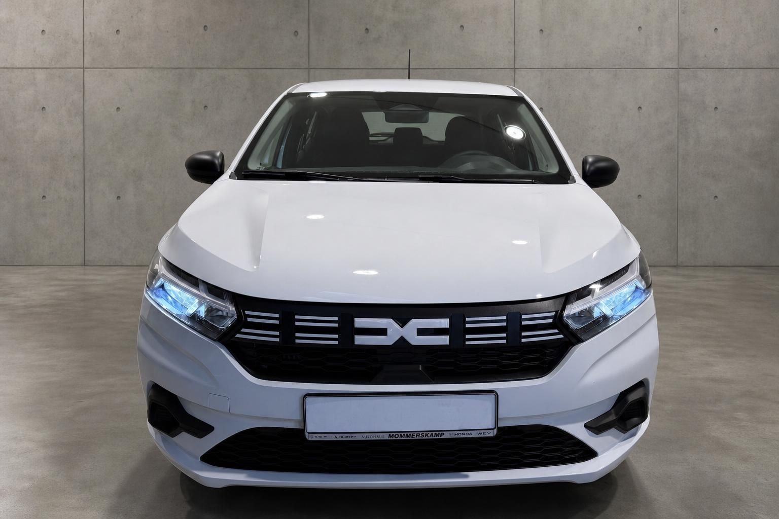 Weißer Dacia von vorne mit LED-Scheinwerfern und Kühlergrill