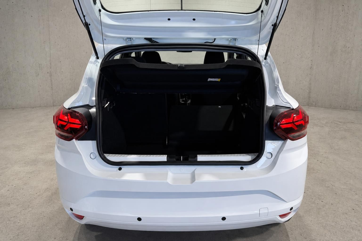 Geöffneter Kofferraum eines weißen Dacia von hinten fotografiert