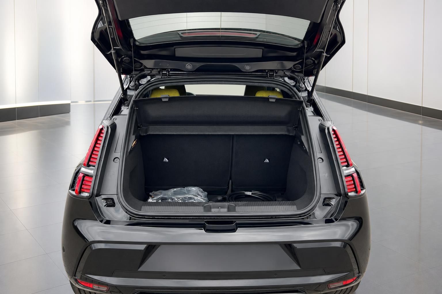 Geöffneter Kofferraum eines schwarzen Elektro-SUV mit Laderaumabdeckung und Ladekabel von hinten