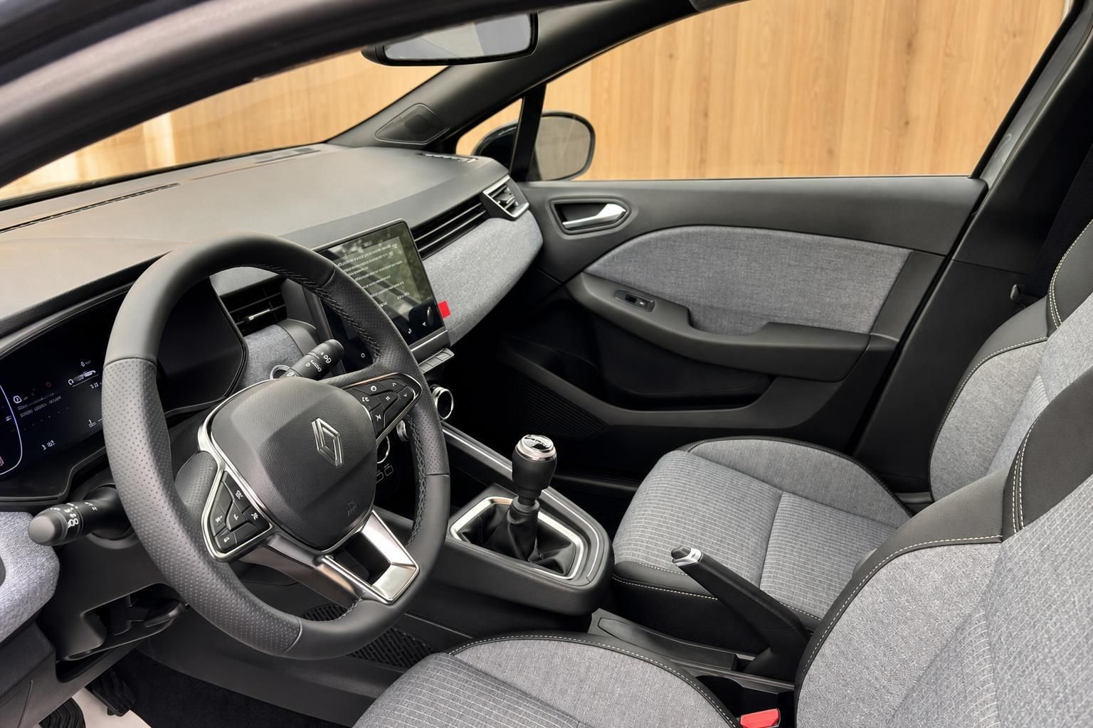 Renault Fahrzeuginnenraum mit Lenkrad, Schaltgetriebe, grauem Stoffsitz und Infotainment-Touchscreen