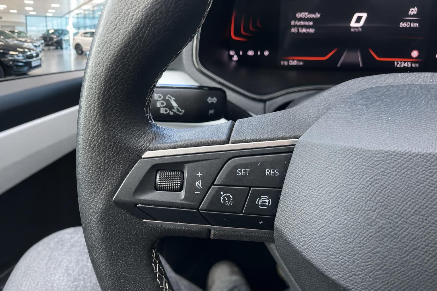 Lenkradbedienung mit Tempomat-Tasten und Display im Fahrzeuginnenraum