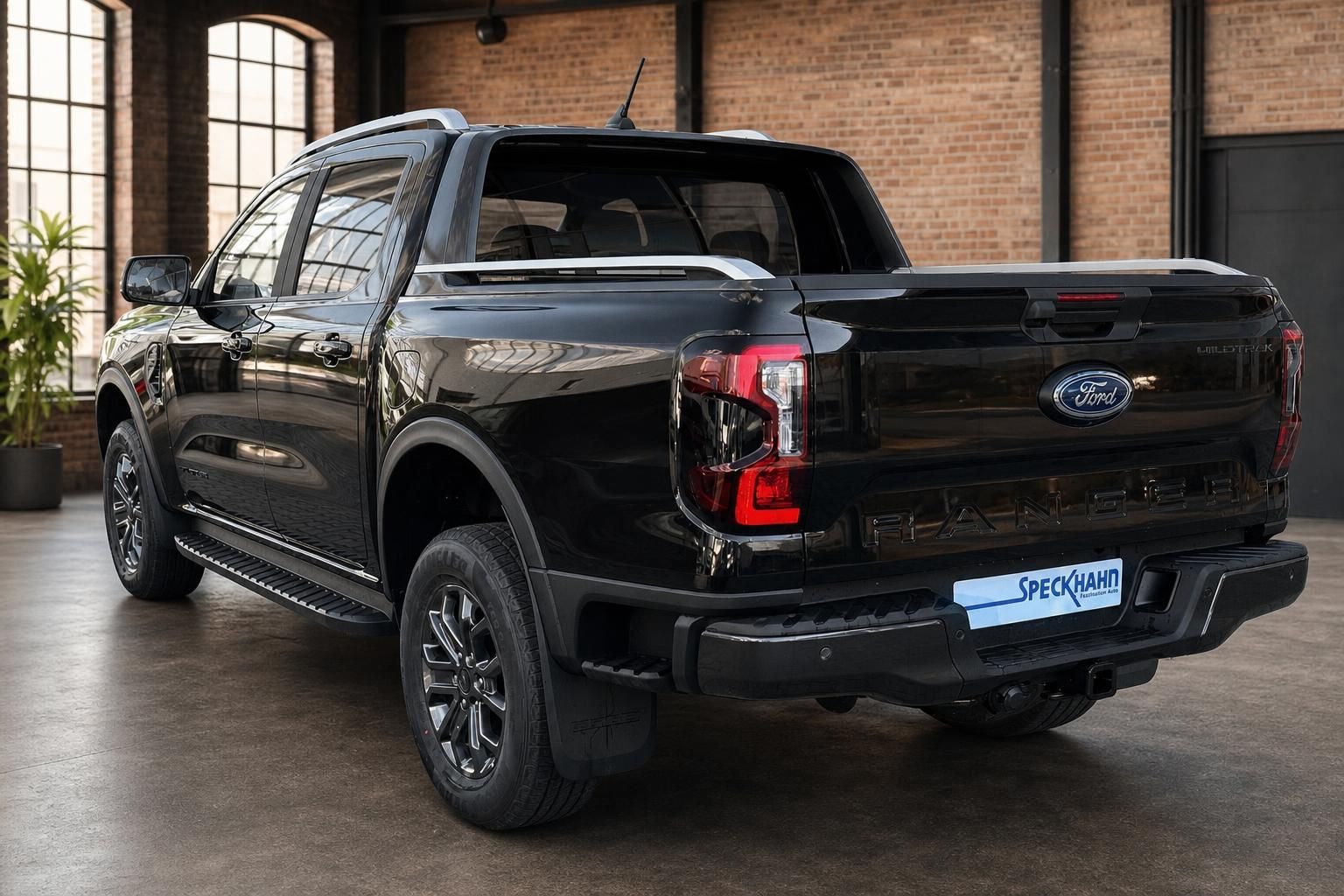 Ford Ranger Wildtrak schwarz Heckansicht schräg im Showroom mit Ladeflächenabdeckung