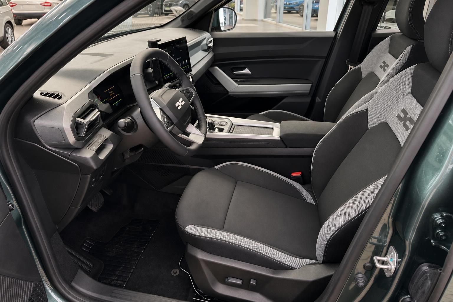 Dacia Bigster Innenraum mit grauen Sitzen, Lenkrad und modernem Cockpit Design