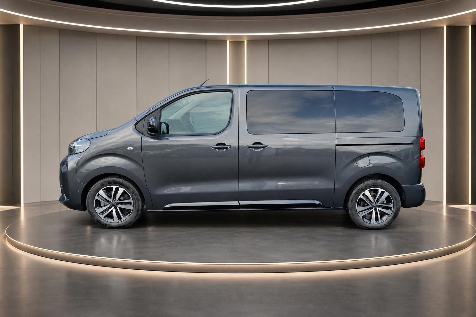 Grauer Personentransporter in Seitenansicht in modernem Showroom mit eleganter Beleuchtung