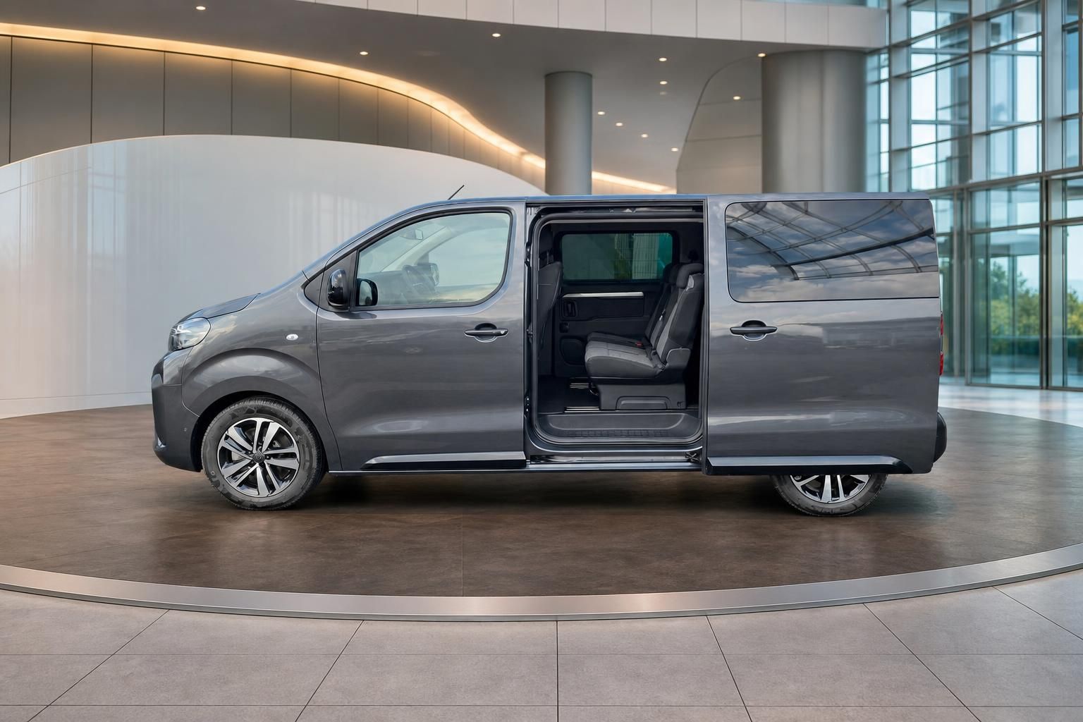 Grauer Van mit geöffneter Schiebetür zeigt komfortable Innenausstattung in modernem Showroom