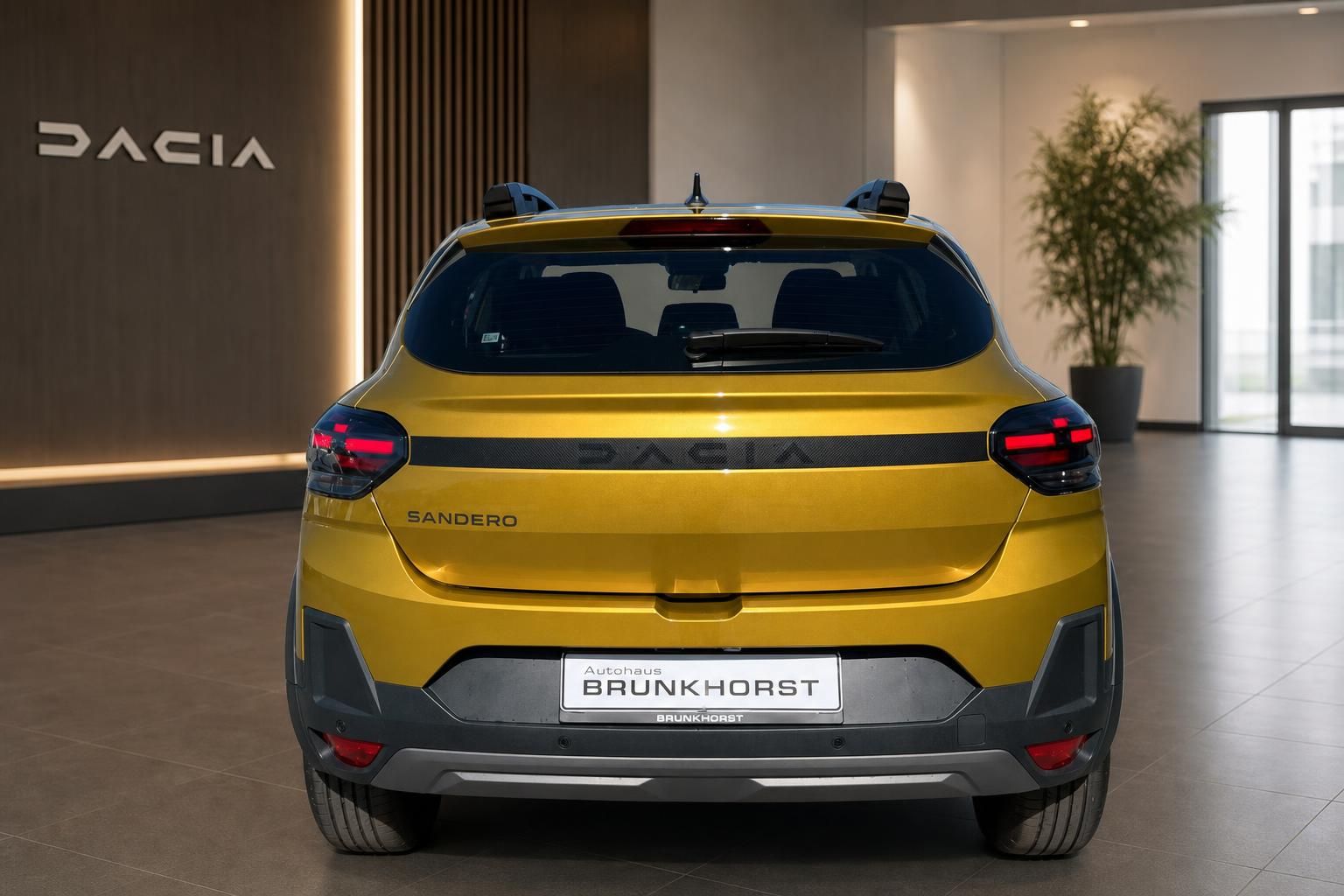 Gelber Dacia Sandero Heckansicht mit LED-Rückleuchten im modernen Autohaus Showroom
