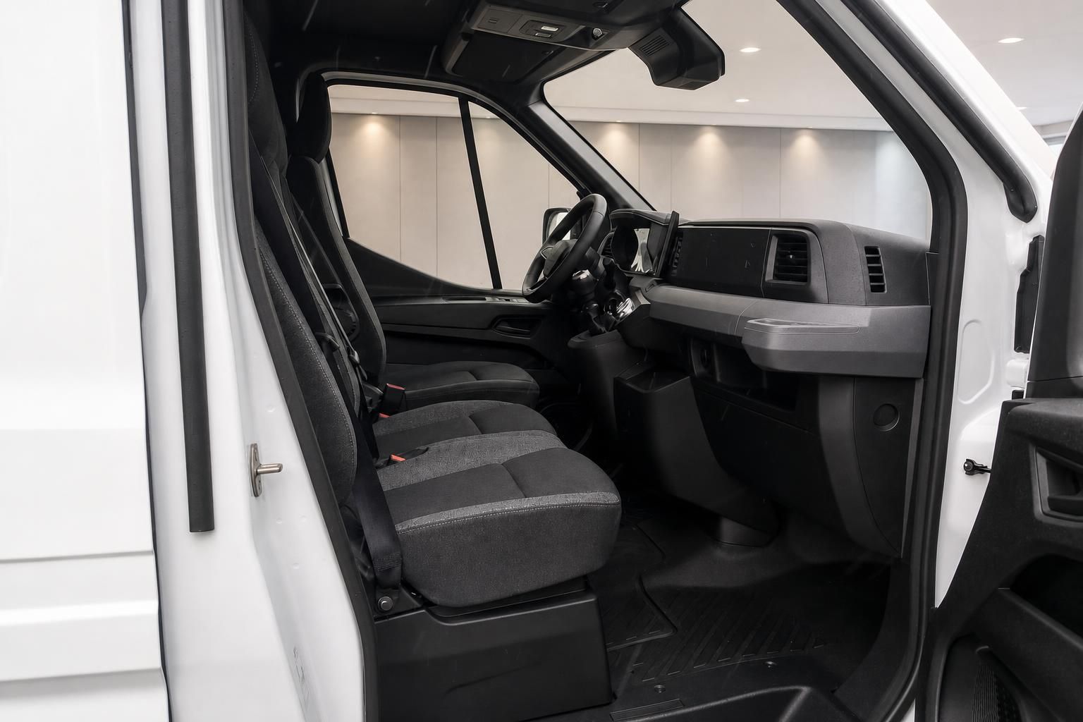 Fahrerhaus-Innenraum eines weißen Transporters mit Doppelsitzbank, Lenkrad und Armaturenbrett