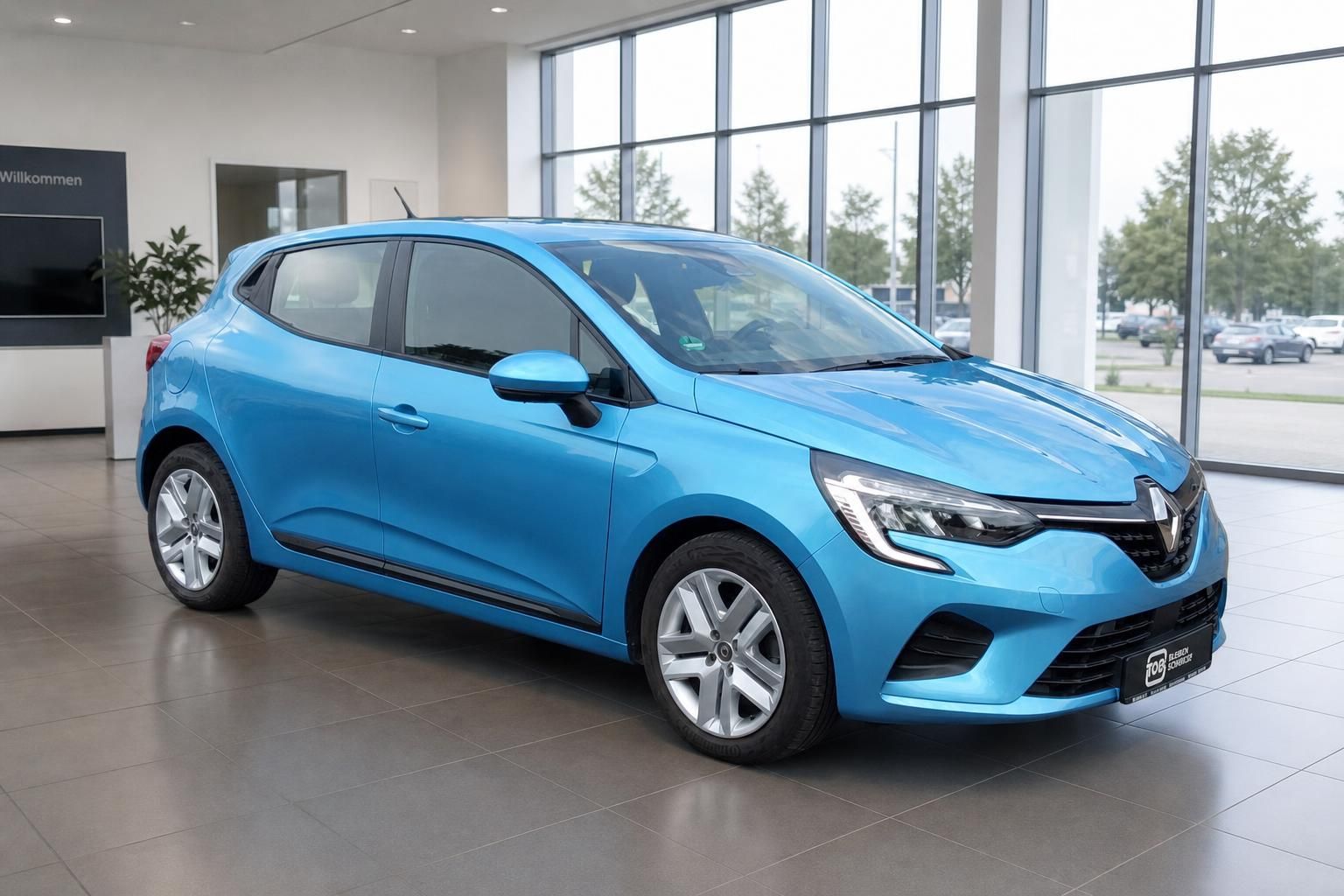 Blauer Renault Clio in modernem Autohaus-Showroom mit großen Fenstern