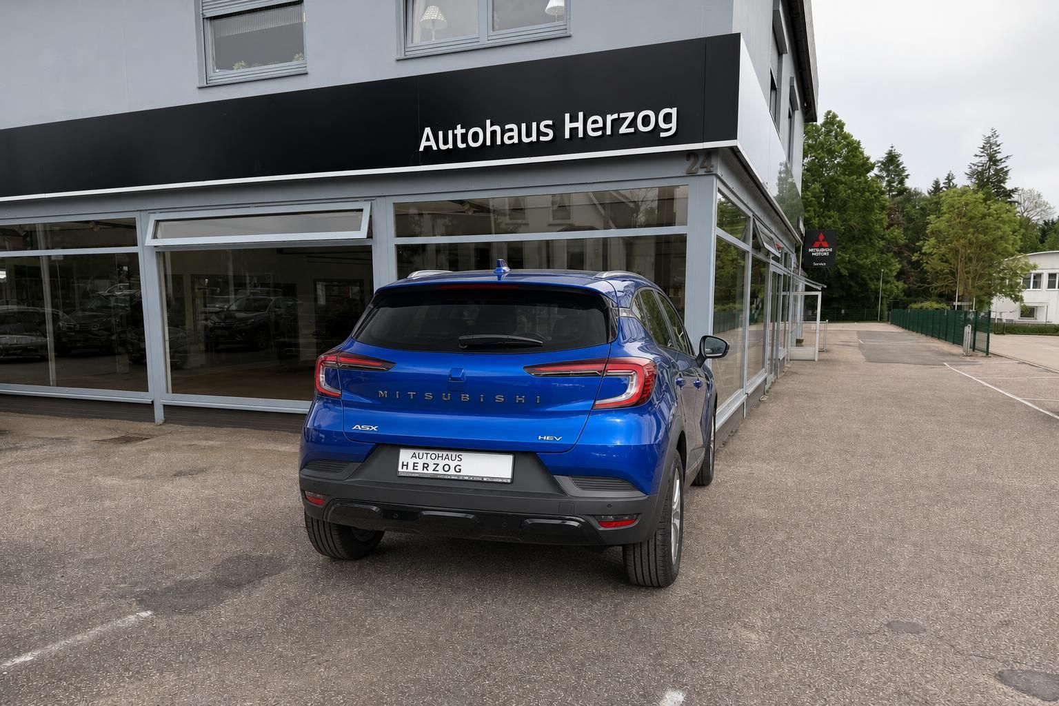Blauer Mitsubishi ASX Heckansicht mit HEV Hybrid-Kennzeichnung vor Autohaus