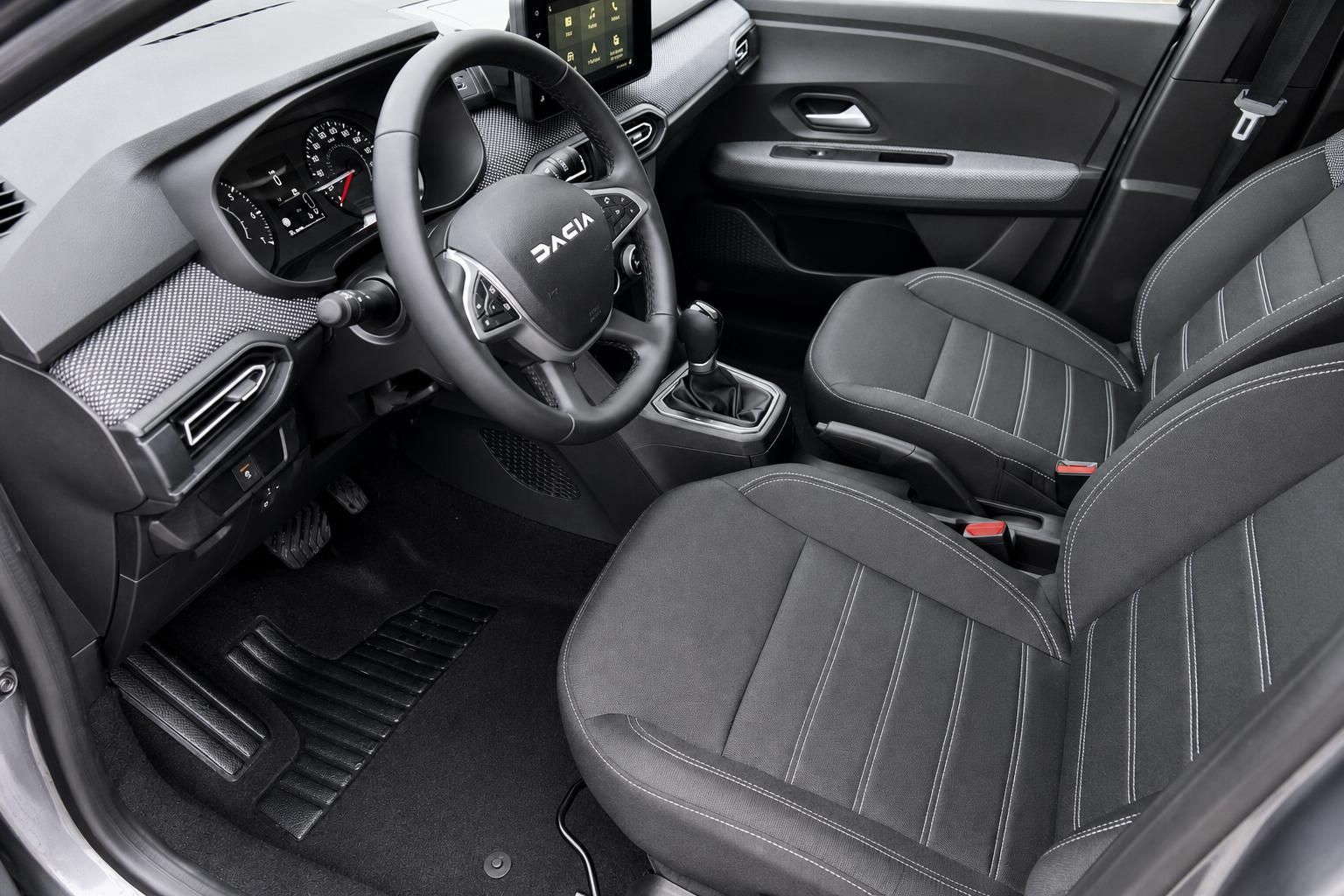 Dacia Sandero Cockpit mit Lenkrad, Schalthebel und grauen Sitzen von der Fahrertür aus