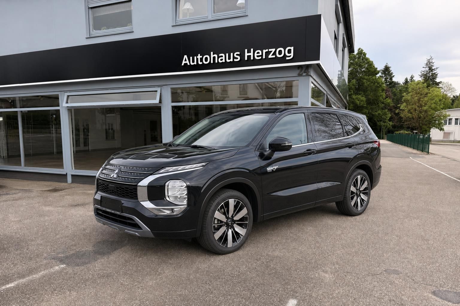 Schwarzer Mitsubishi SUV vor Autohaus Herzog Verkaufsgebäude