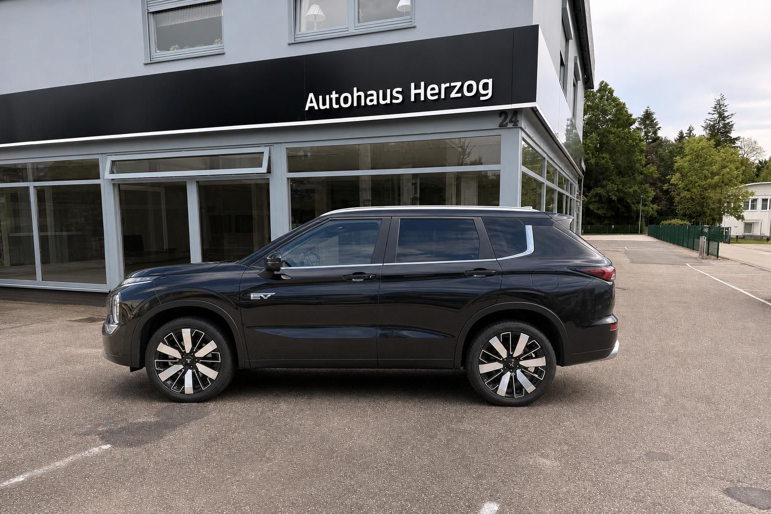 Mitsubishi Outlander PHEV SUV schwarz, Seitenansicht mit EV-Kennzeichnung vor Autohaus