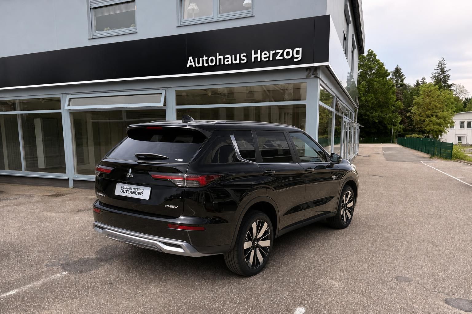 Mitsubishi Outlander PHEV SUV schwarz, schräge Heckansicht vor Autohaus Herzog