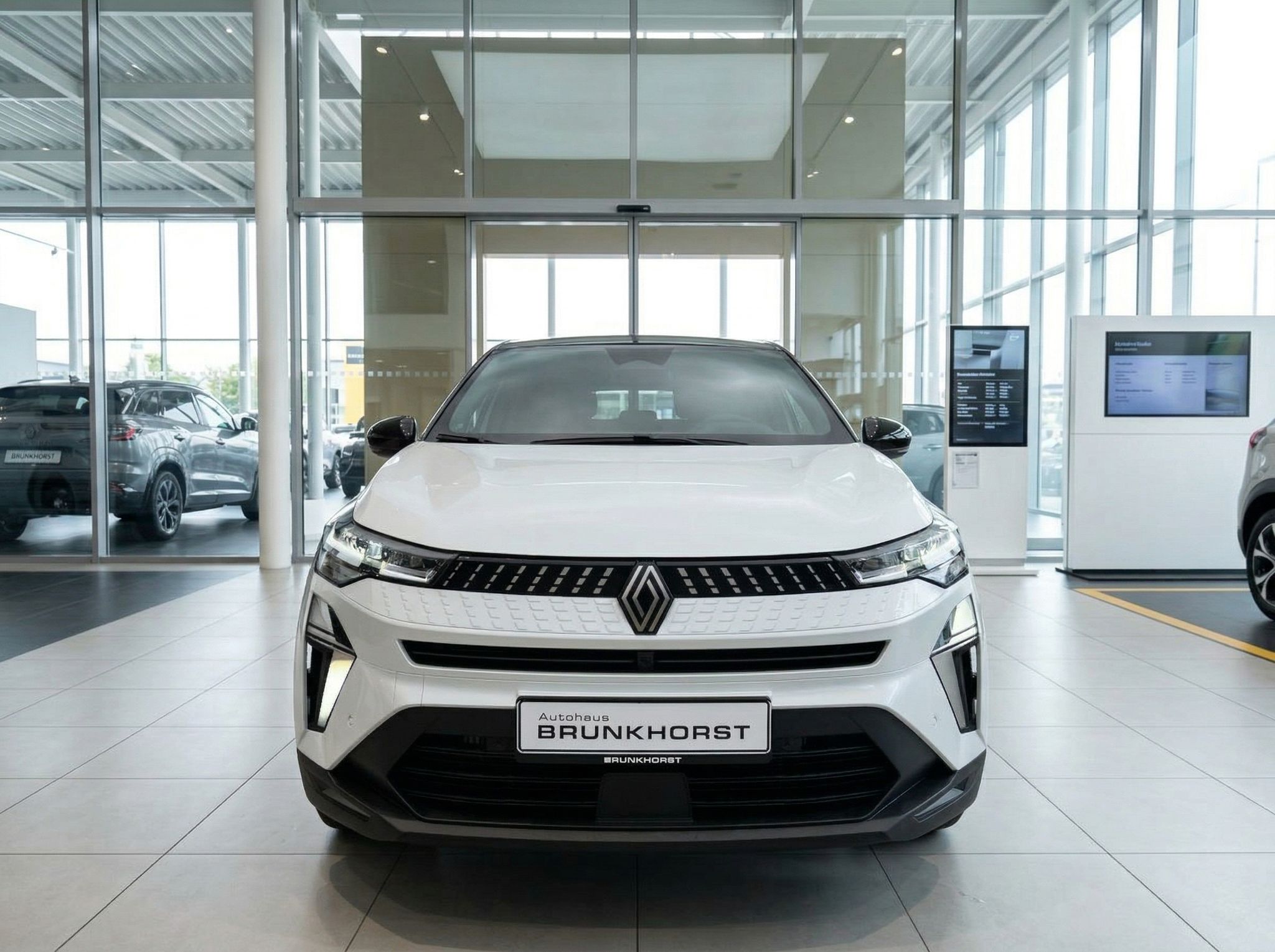 Renault Captur weiss Frontansicht im Showroom, charakteristischer Kühlergrill und LED-Scheinwerfer