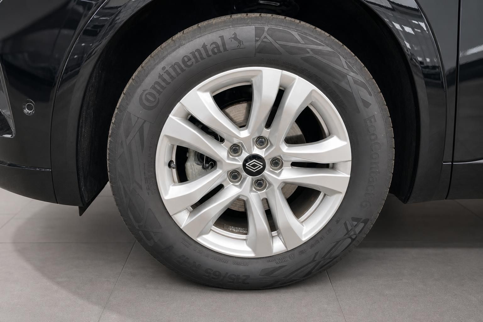 Fahrzeugfelge mit Continental Reifen, Alufelge und schwarzer Fahrzeugkarosserie im Autohaus