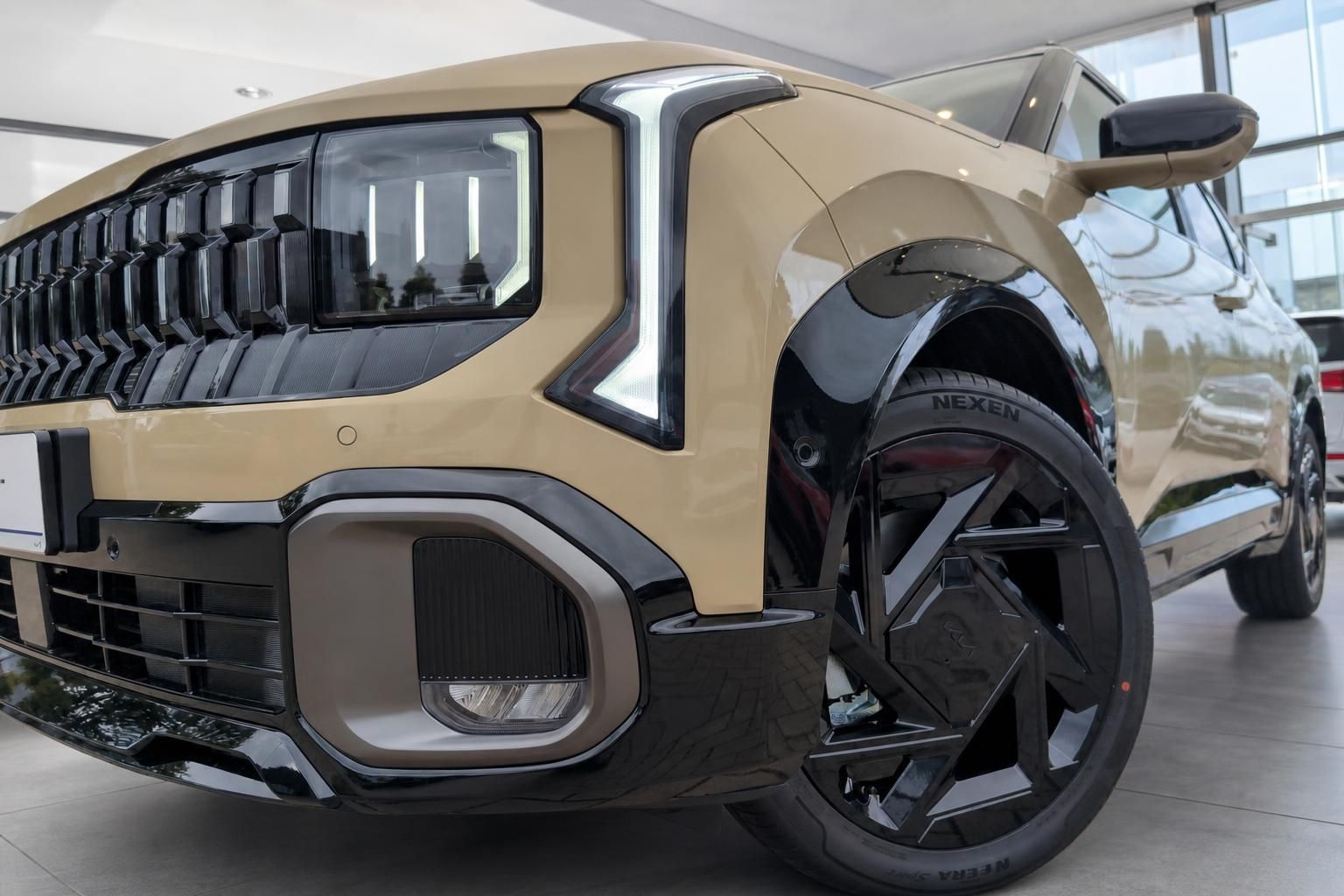 Kia SUV in Beige mit schwarzer Frontpartie und Alufelgen im Detail