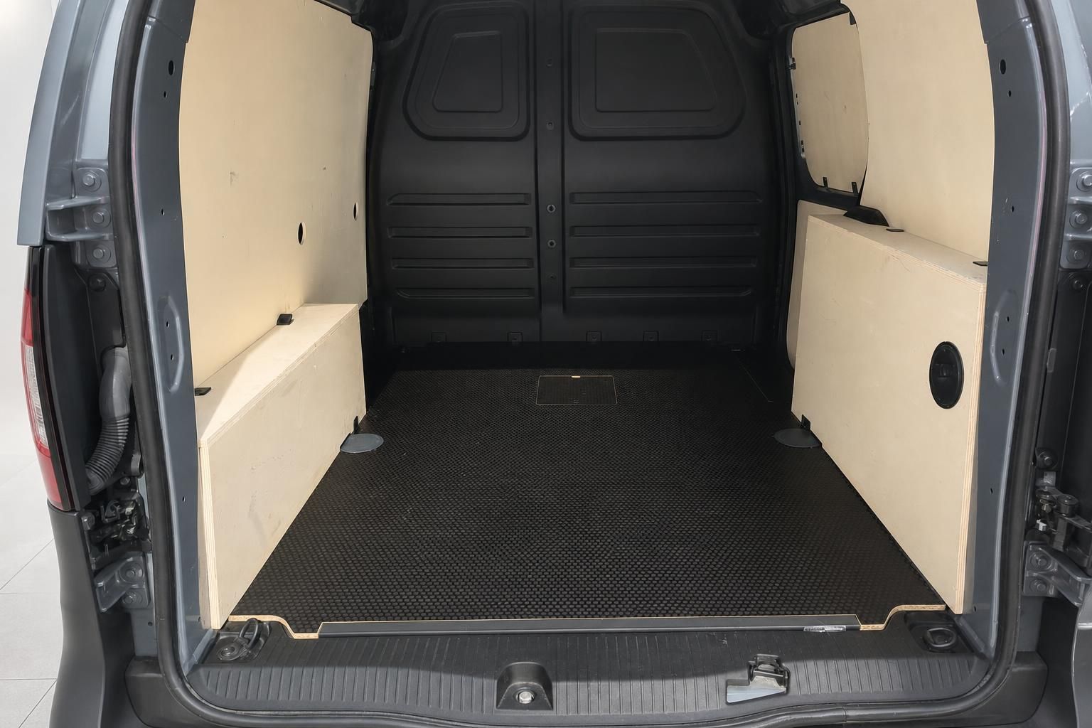 Geräumiger Laderaum eines Transporters mit schwarzer Gummimatte und beigen Seitenwänden