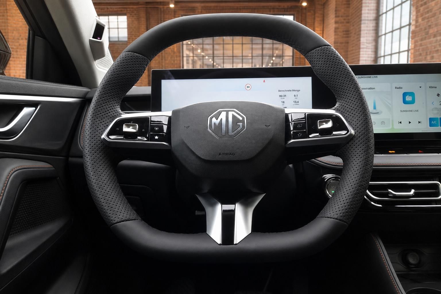 MG Lenkrad mit Logo, Multifunktionstasten und Touchscreen-Display im Hintergrund