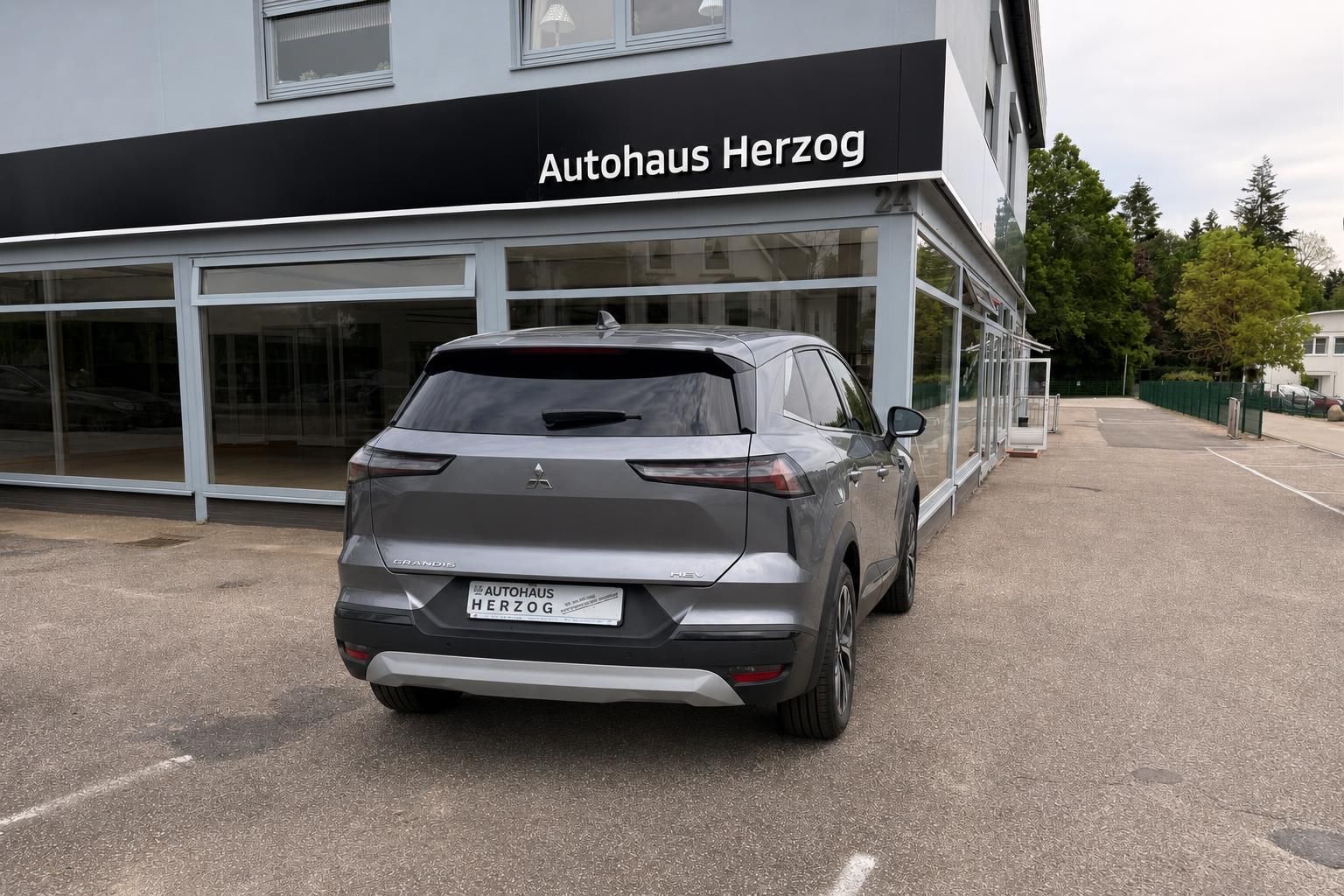 Grauer SUV Heckansicht schräg vor Autohaus Herzog mit Kennzeichen
