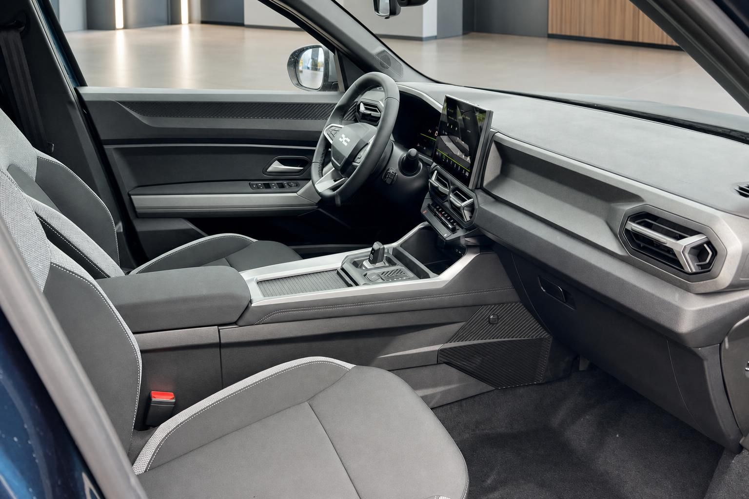 Moderner Fahrzeuginnenraum mit grauer Ausstattung, Touchscreen und Schaltknauf