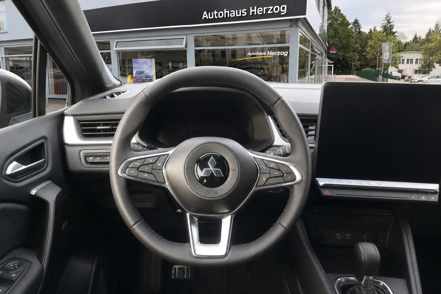 Detailaufnahme Fahrzeug Lenkrad mit Mitsubishi Logo und Bedienelemente