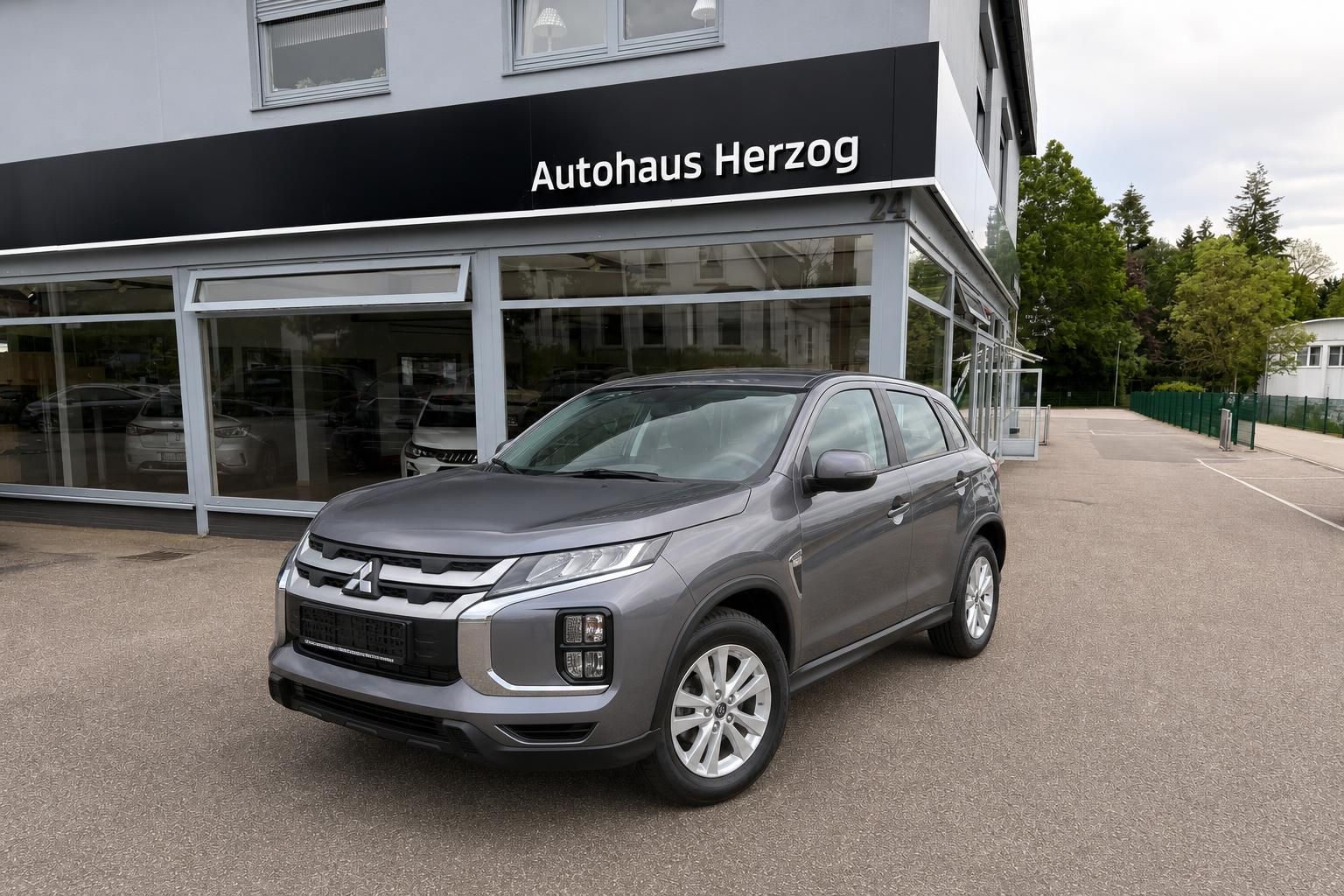 Grauer Mitsubishi SUV vor Autohaus Herzog - Gebrauchtwagen mit Allradantrieb