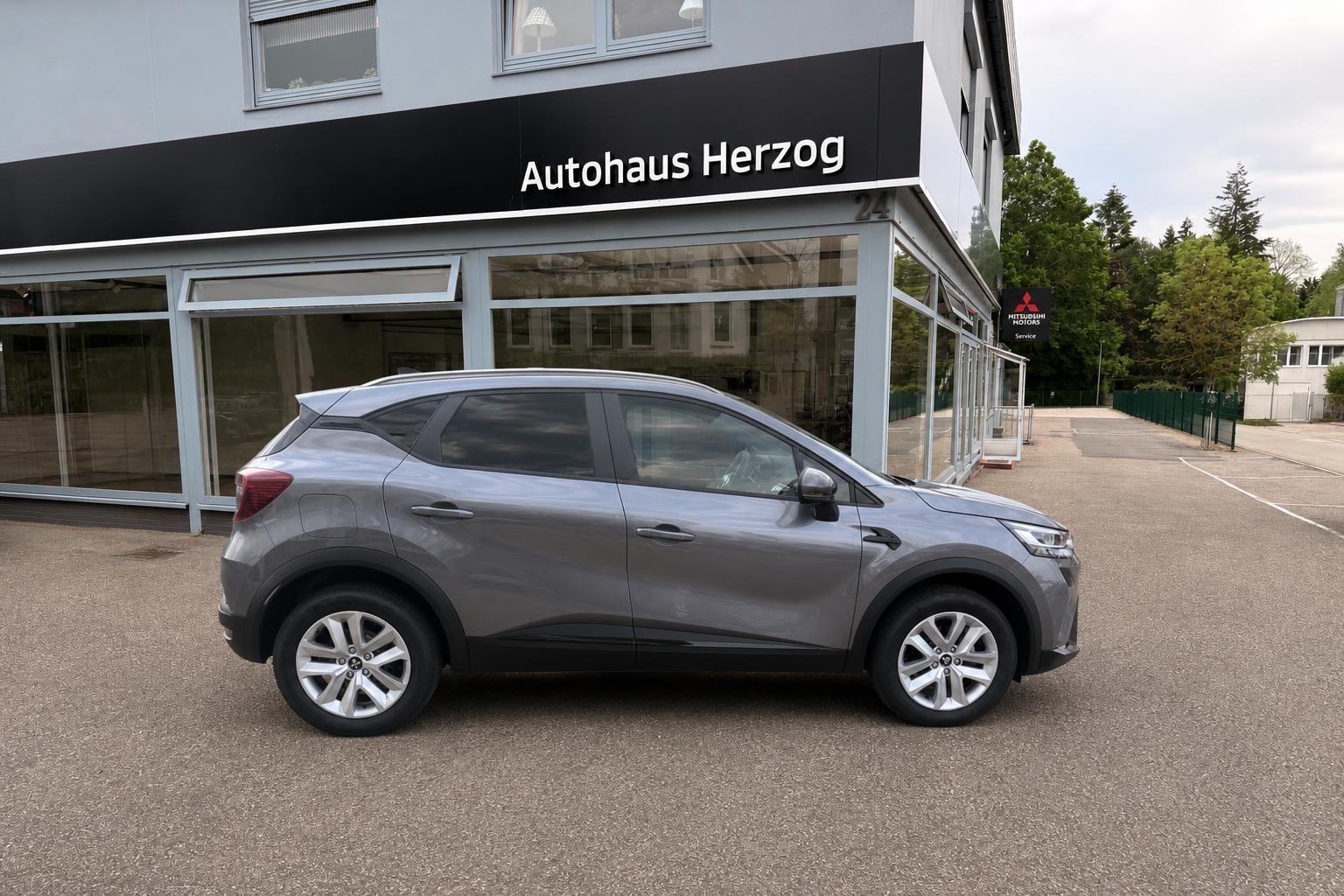 Grauer Mitsubishi SUV Seitenansicht vor Autohaus Herzog Gebäude