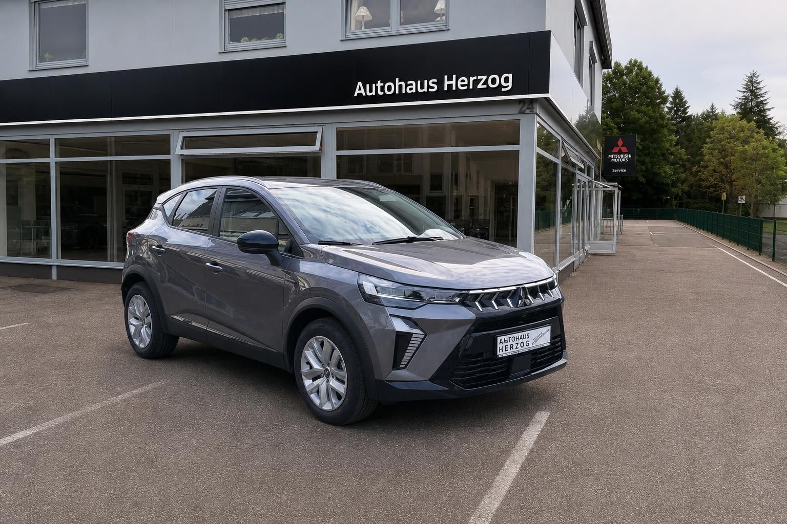 Mitsubishi ASX Crossover in grau - Seitenansicht vor modernem Autohaus mit großen Fenstern