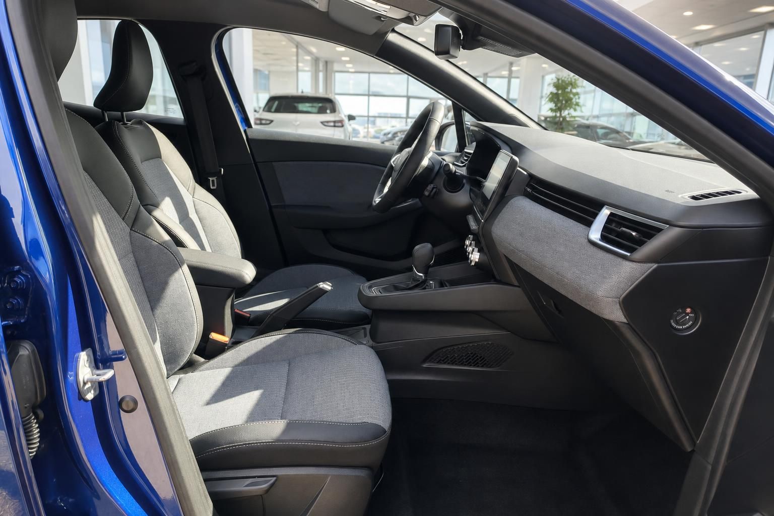 Innenraum eines blauen Renault Fahrzeugs mit grauer Sitzausstattung und modernem Dashboard im Autohaus