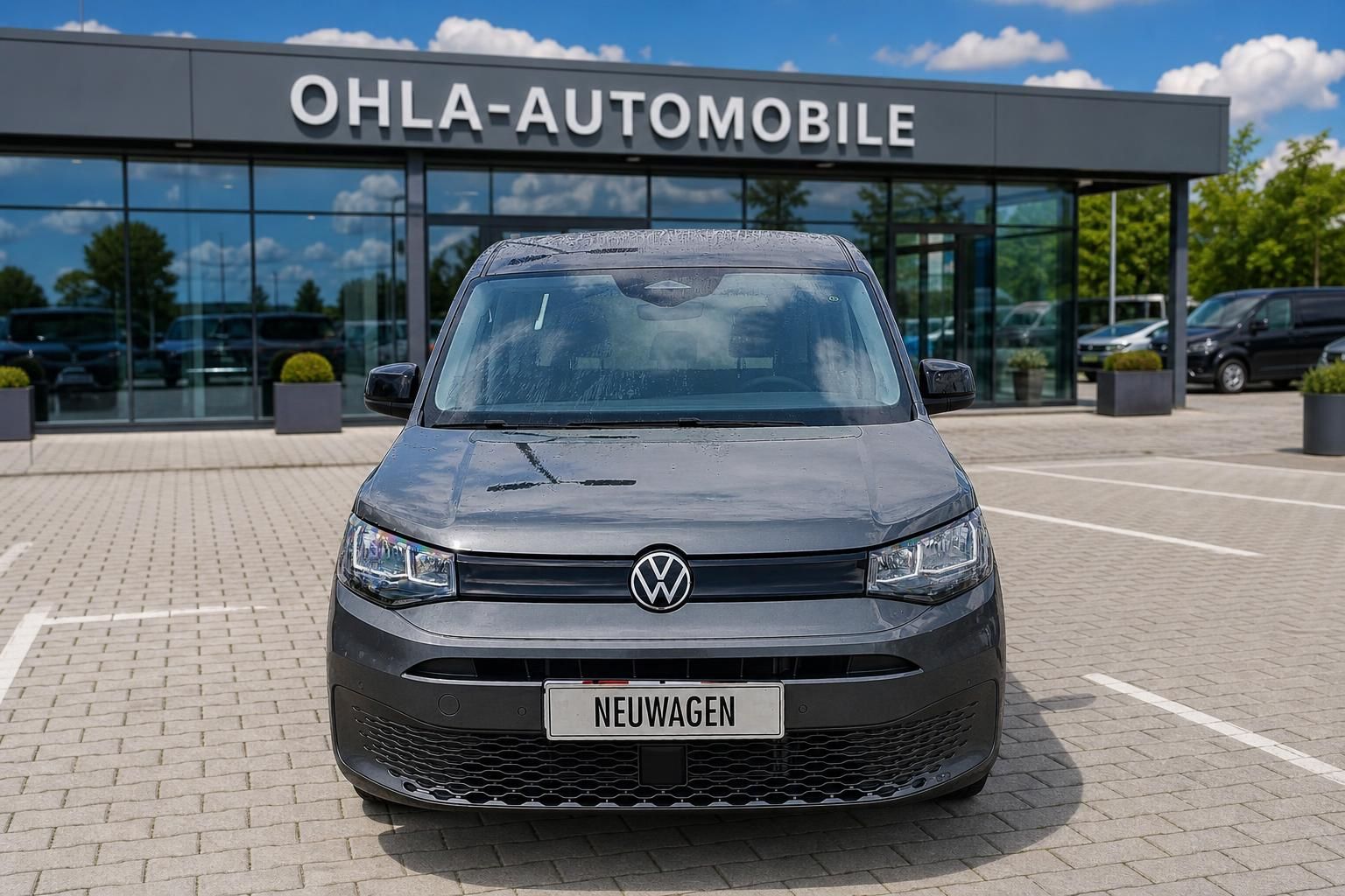 VW Caddy grau Frontansicht mit VW Logo vor Autohaus