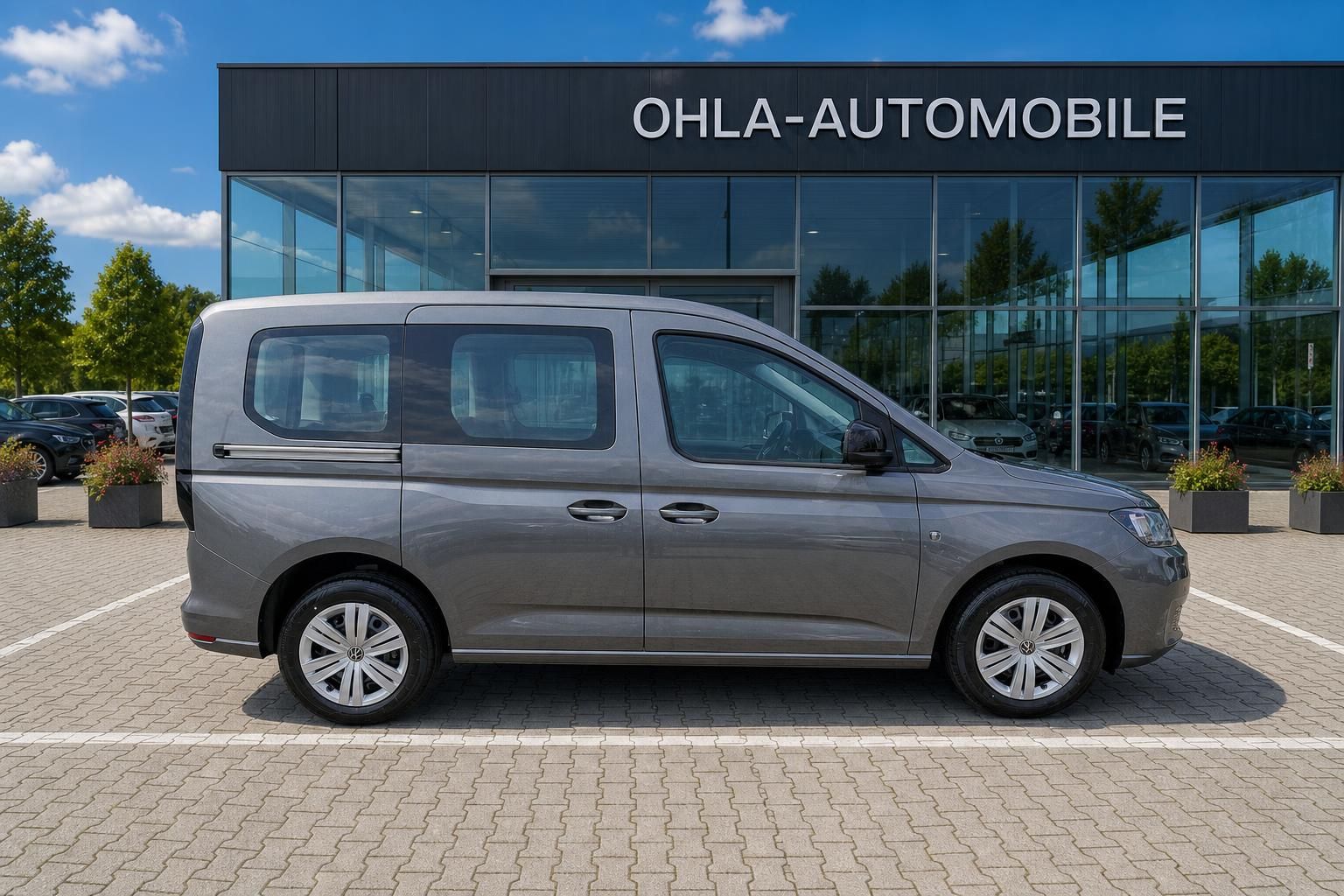 VW Caddy grau Seitenansicht vor Autohaus Ohla-Automobile