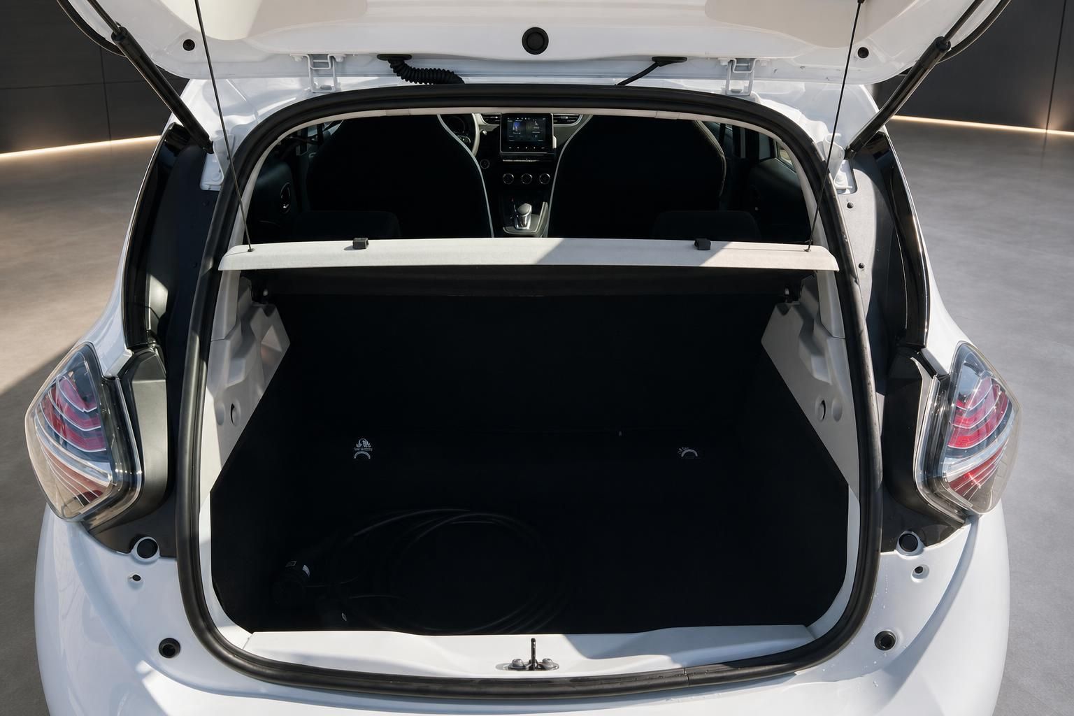 Kofferraum eines weißen Elektroautos mit geöffneter Heckklappe und schwarzer Innenausstattung