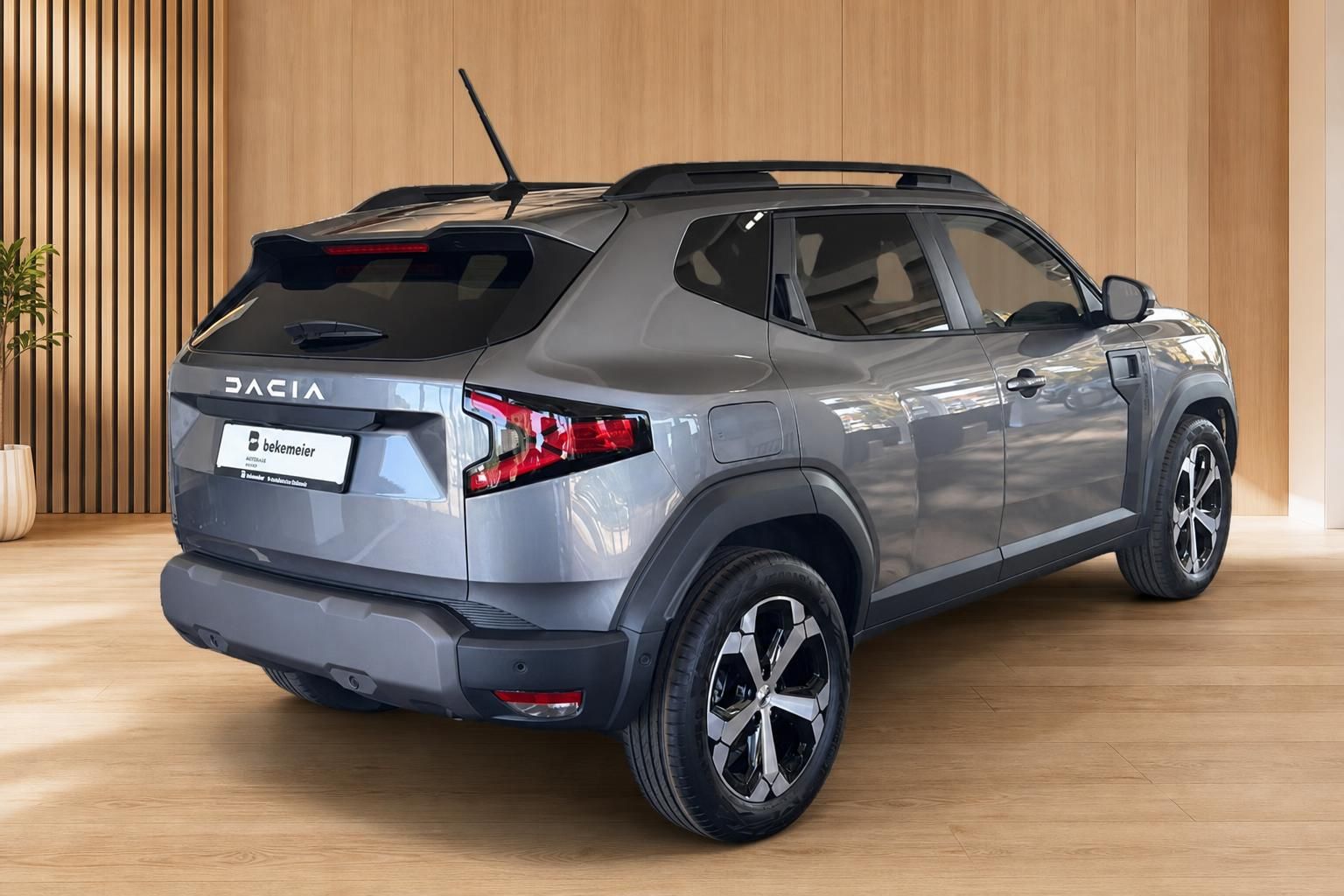 Dacia Duster grau Heckansicht schräg im Showroom – SUV mit Dachrellings und Leichtmetallfelgen