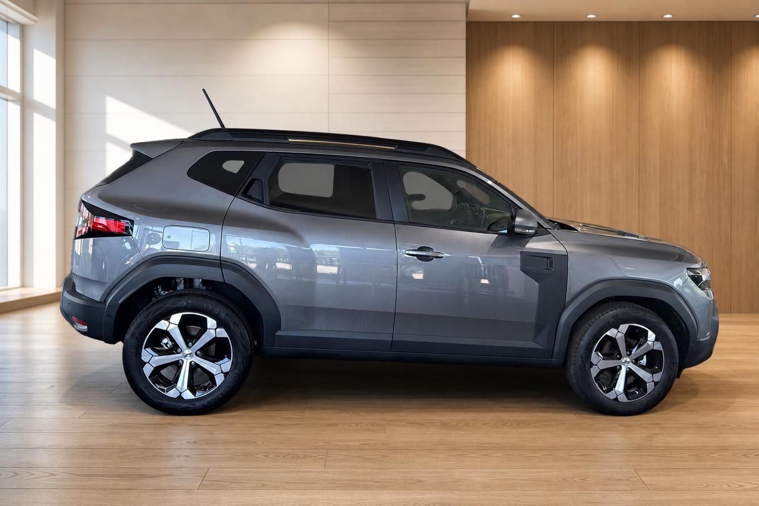 Dacia Duster grau Seitenansicht im Showroom – SUV mit schwarzem Dach und Leichtmetallfelgen