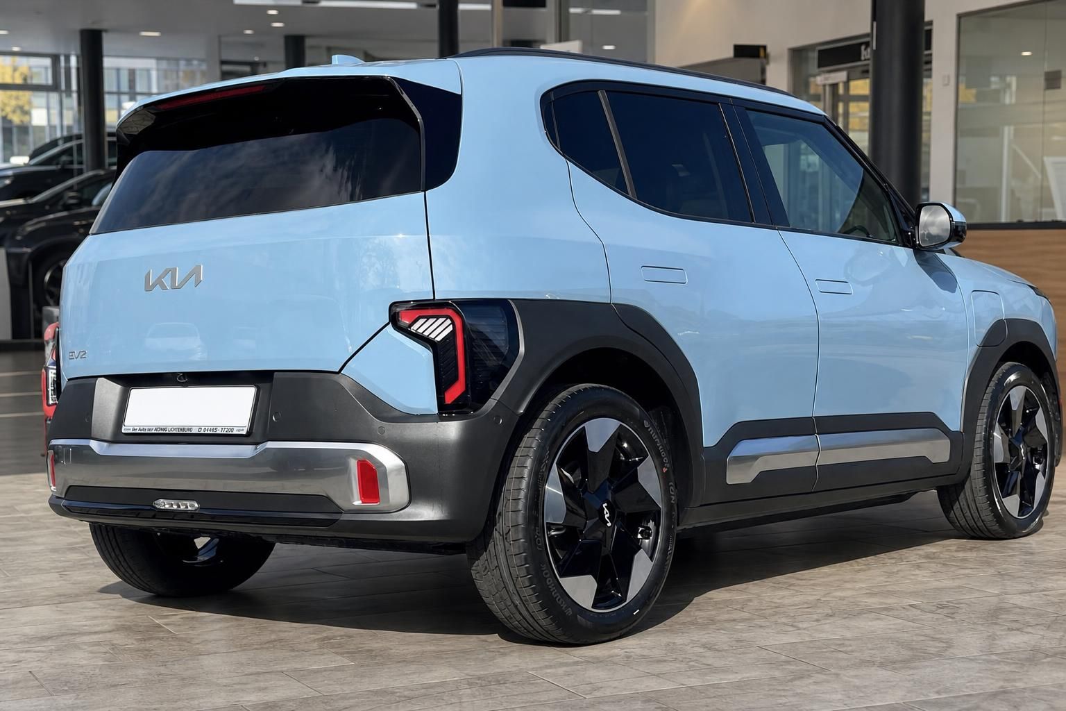 Kia EV3 in Hellblau, Heck-Seitenansicht mit schwarzen Felgen