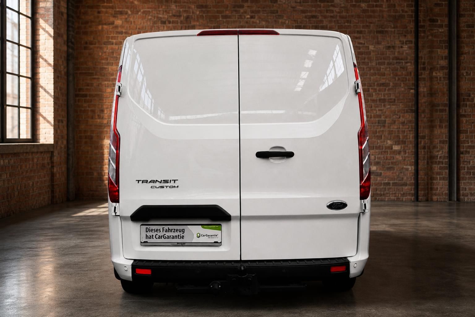 Ford Transit Custom Kastenwagen weiss Heckansicht gerade in Industriehalle mit Anhaengerkupplung
